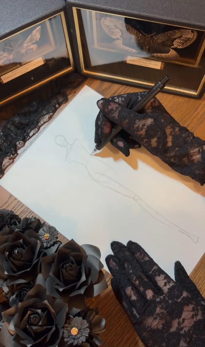 黒いレースの手袋を着け、服のデザイン画を描く手元