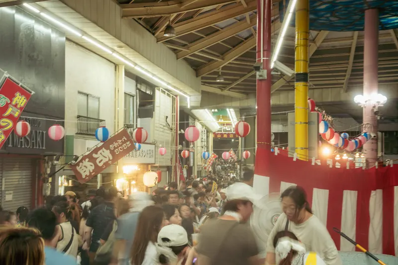 紅白の櫓と提灯の周囲に集まる湊川夜市の人々