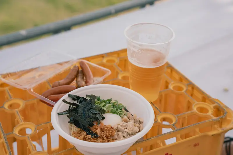 かっ祭の冷やしまぜそばとソーセージ、ビール。テーブル代わりのビールケースの上で