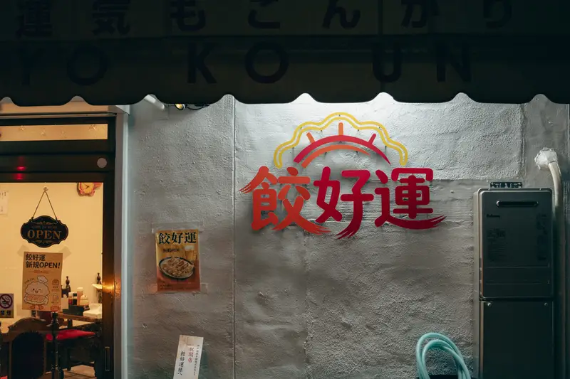 餃好運の店頭。白い庇に赤いロゴが入る
