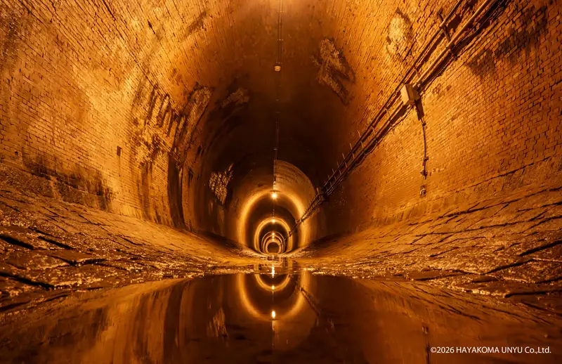 Inside Minatogawa Zuido — the brick-lined passage and its mirror-like water surface