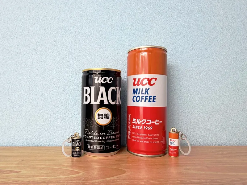 実物の缶と並べた「BLACK無糖」と「ミルクコーヒー」のミニチュア