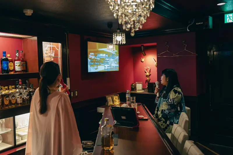A guest singing karaoke with the Mama at Snack Jane